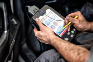 Ilustracyjne zdjęcie mechanika korzystającego z komputera diagnostycznego – symbol rezerwacji online